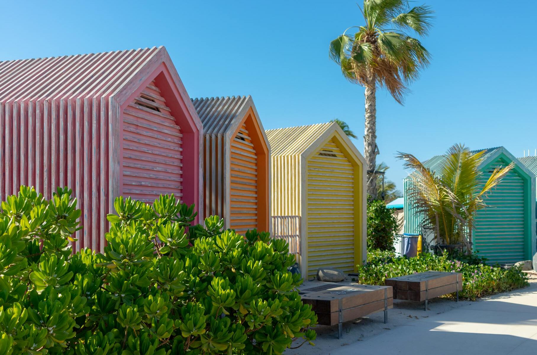 colorful beach huts near green trees under blue sky